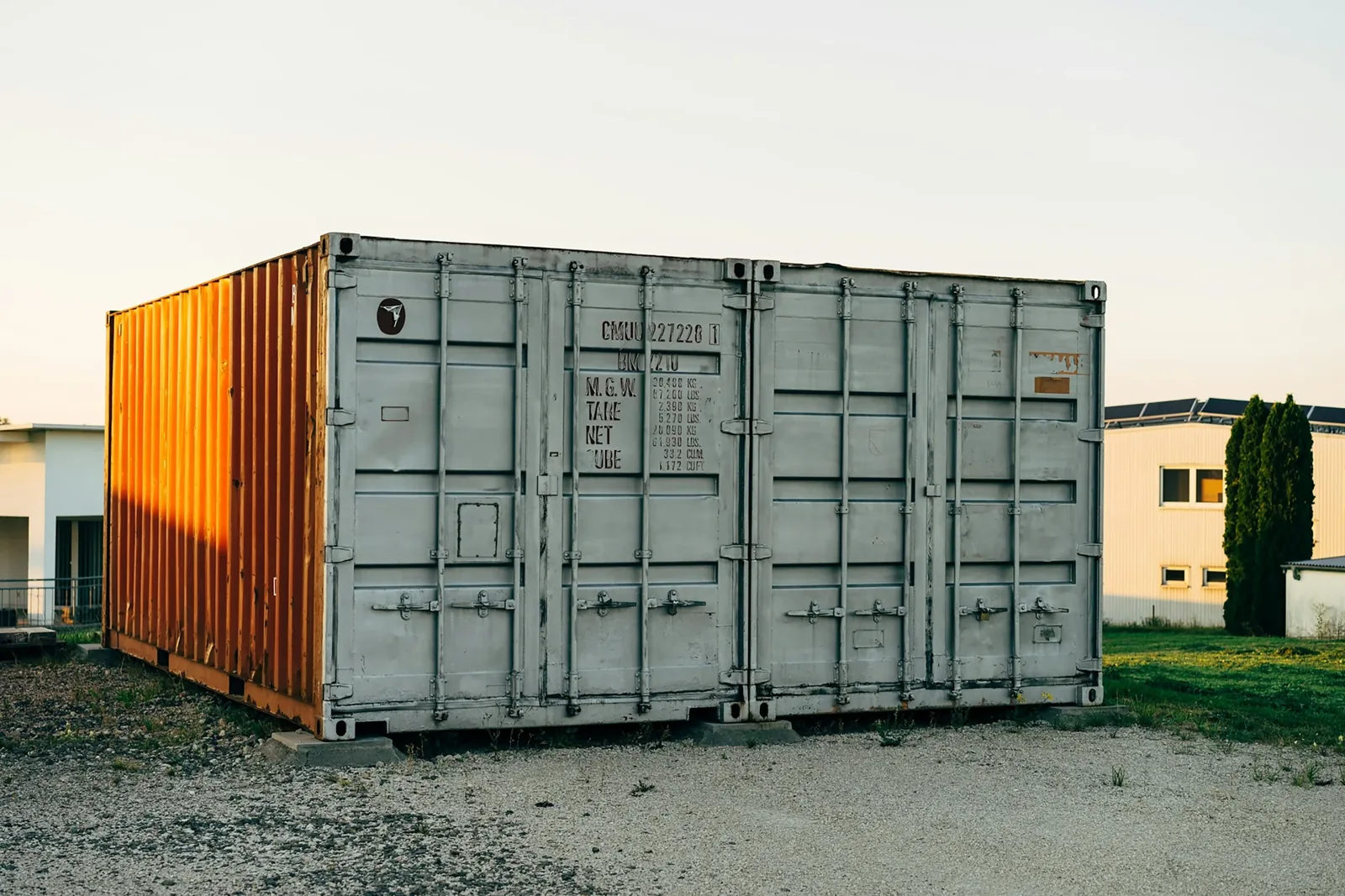 Ground-level steel storage containers on a gravel surface